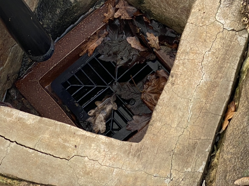 A roof water down pipe gully surround that has sunken and is not longer effective.