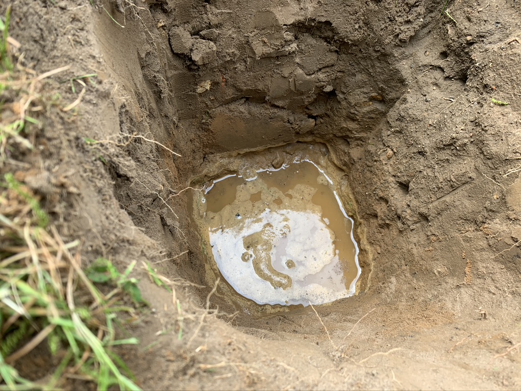 A test hole dug during porosity testing to establish if the ground is suitable for drainage.