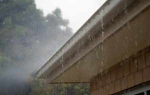 This image shows rainwater pouring over the side of roof guttering.