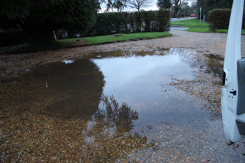 This image shows a driveway with standing or ponding water due to no drainage.