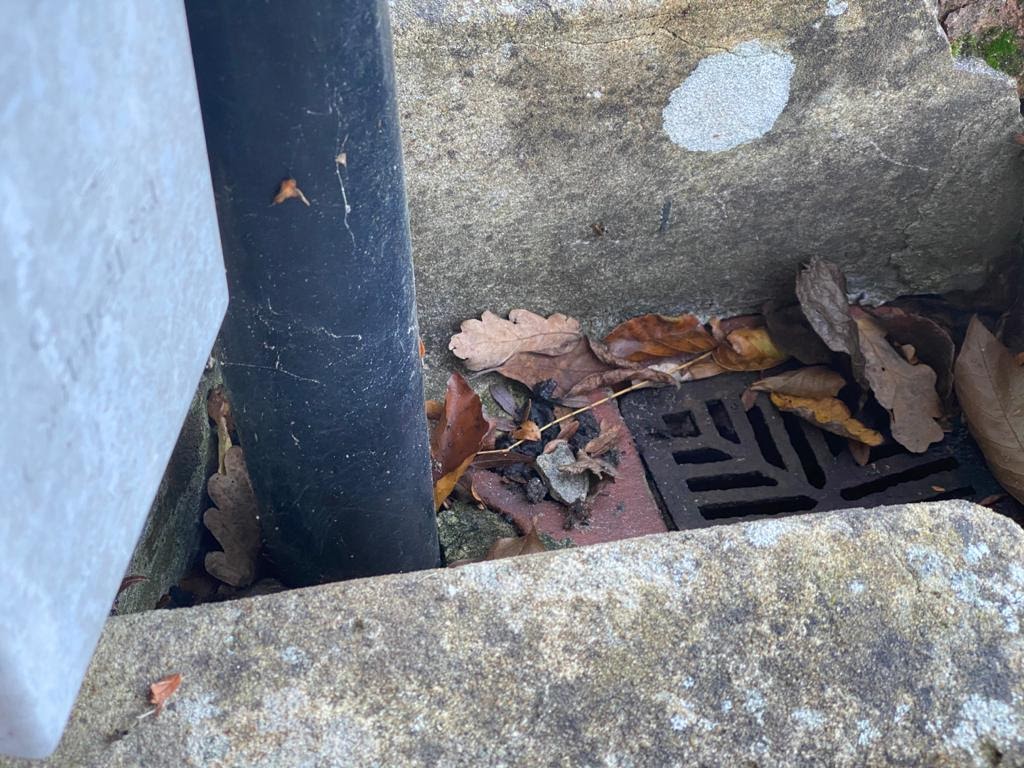 An image of a down pipe entering a gully drain to prevent water pooling around the footings of the house.