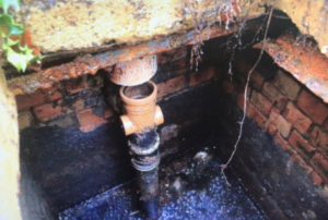 This image shows an old septic tank with a broken dip pipe
