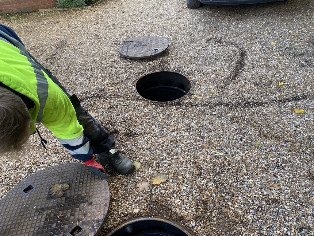 This image shows a cover being removed to reveal the inspection chamber of an old cesspit.