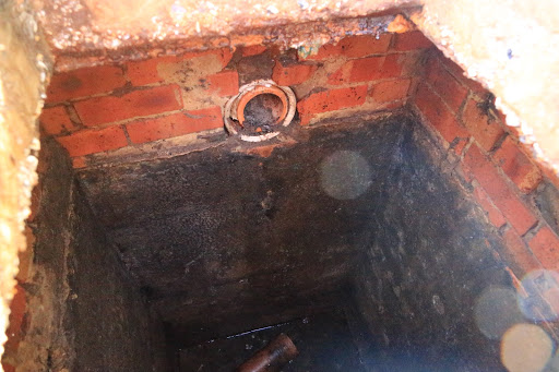 An image of an old brick septic tank with broken dip pipes.
