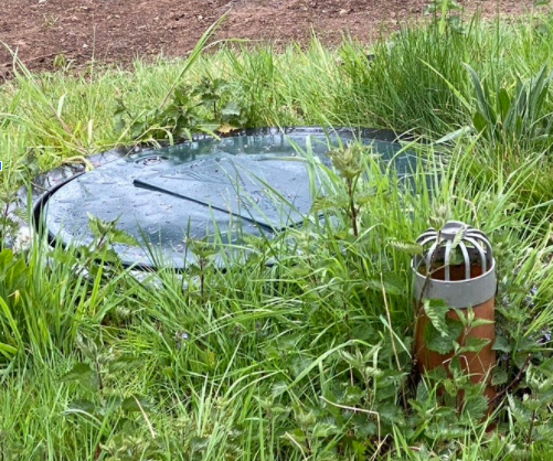 This image shows a vent pipe protruding from the grass next to the treatment plant.