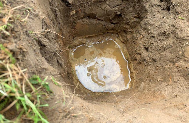 Testing the porosity of the ground to determine if a drainage field is suitable.