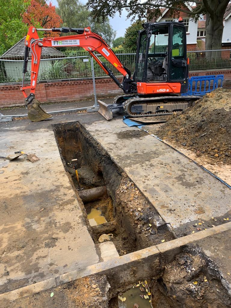 This image shows a digger having dug a trench for a main drain connectiion.