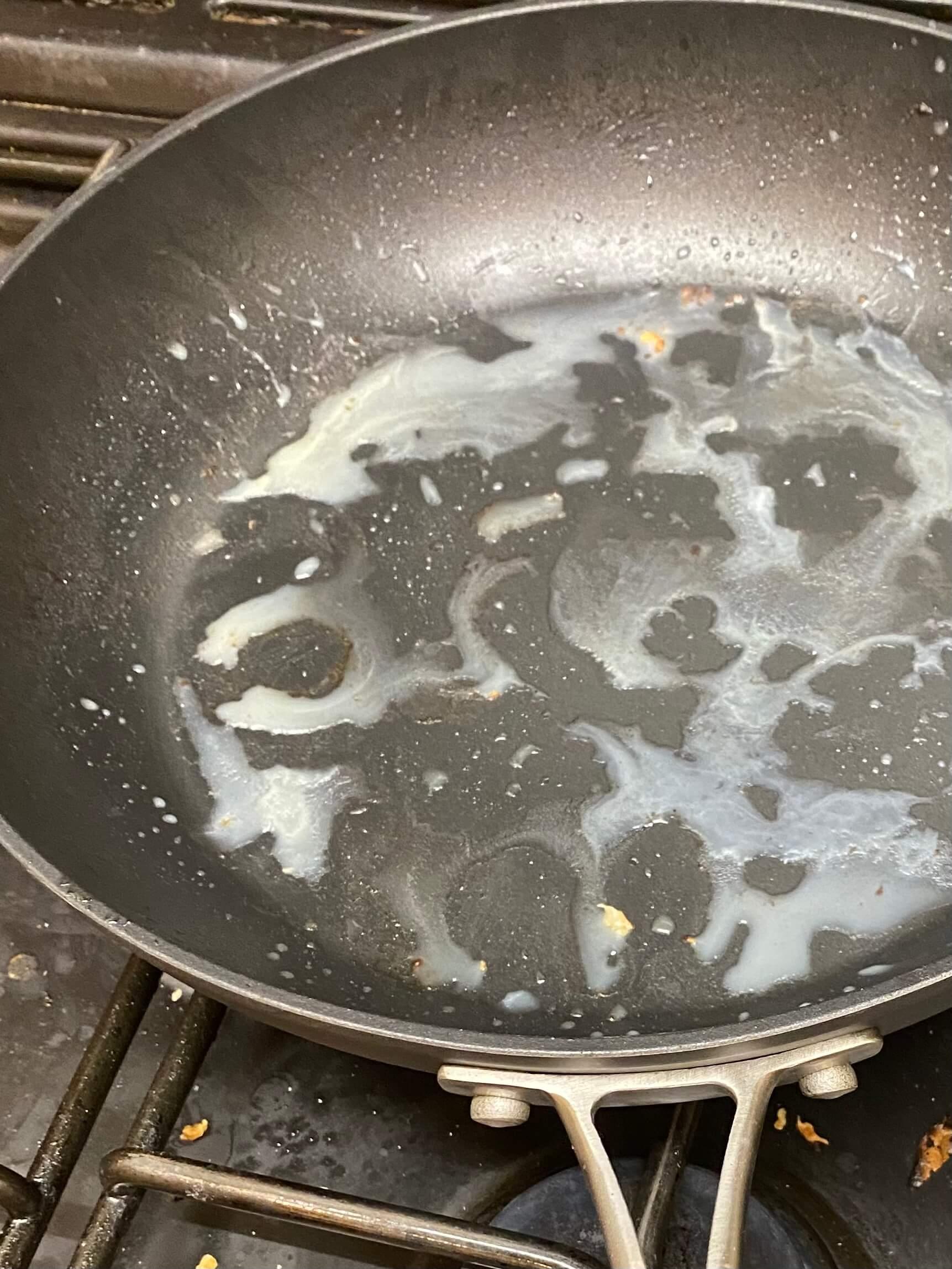 An image of fat residue in a frying pan about to be washed down the sink